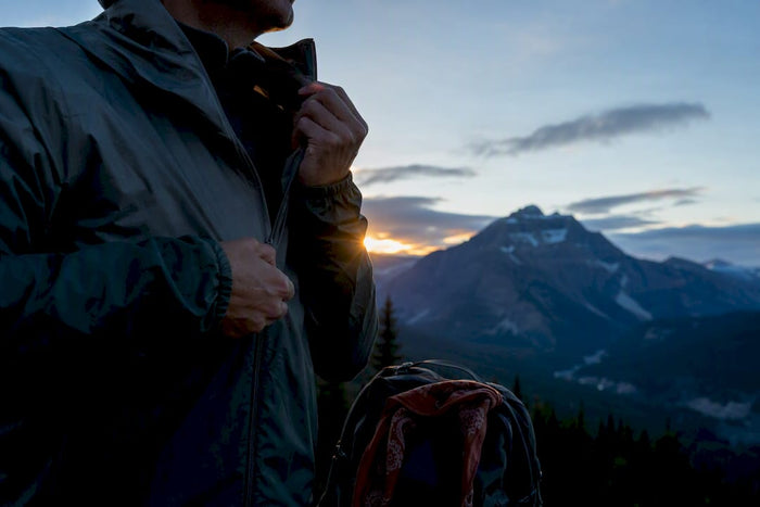 Hiker layering at a Glacier dawn trailhead