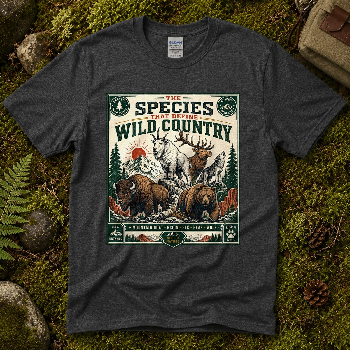 Dark heather grey Wild Country Species tee laid flat on green moss with ferns, river stones and pinecones, showing a vintage badge of a mountain goat, bison, elk, bear and wolf