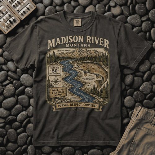 Pepper Madison River Montana trout tee on river stones beside a fly box, showing the river map and leaping brown trout