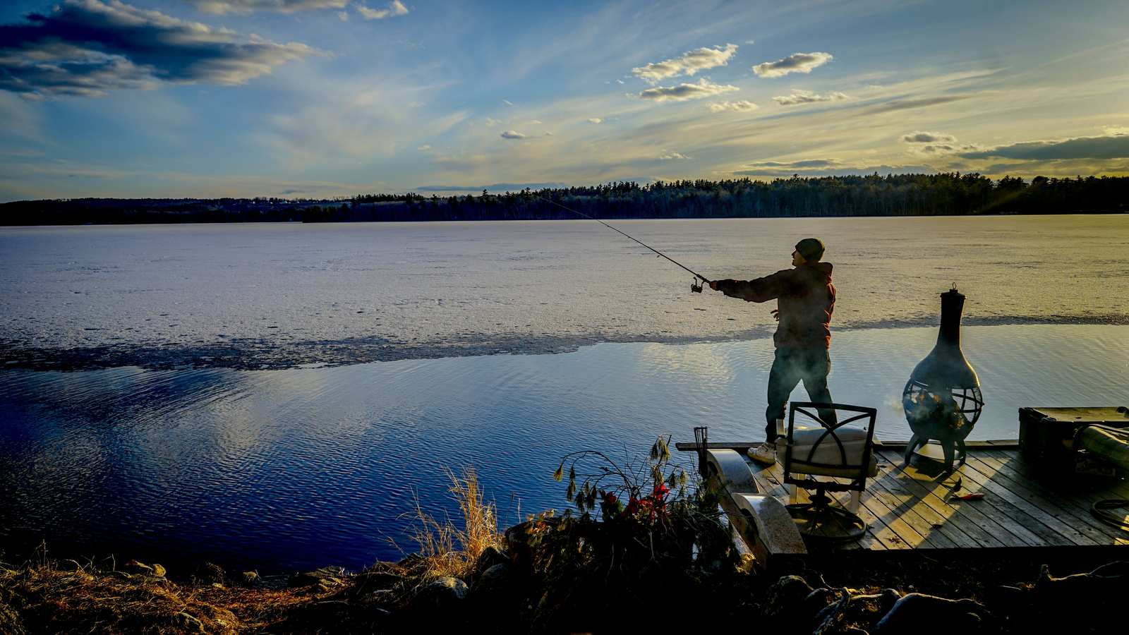 Angler landing a fish from a wooden pier at first light